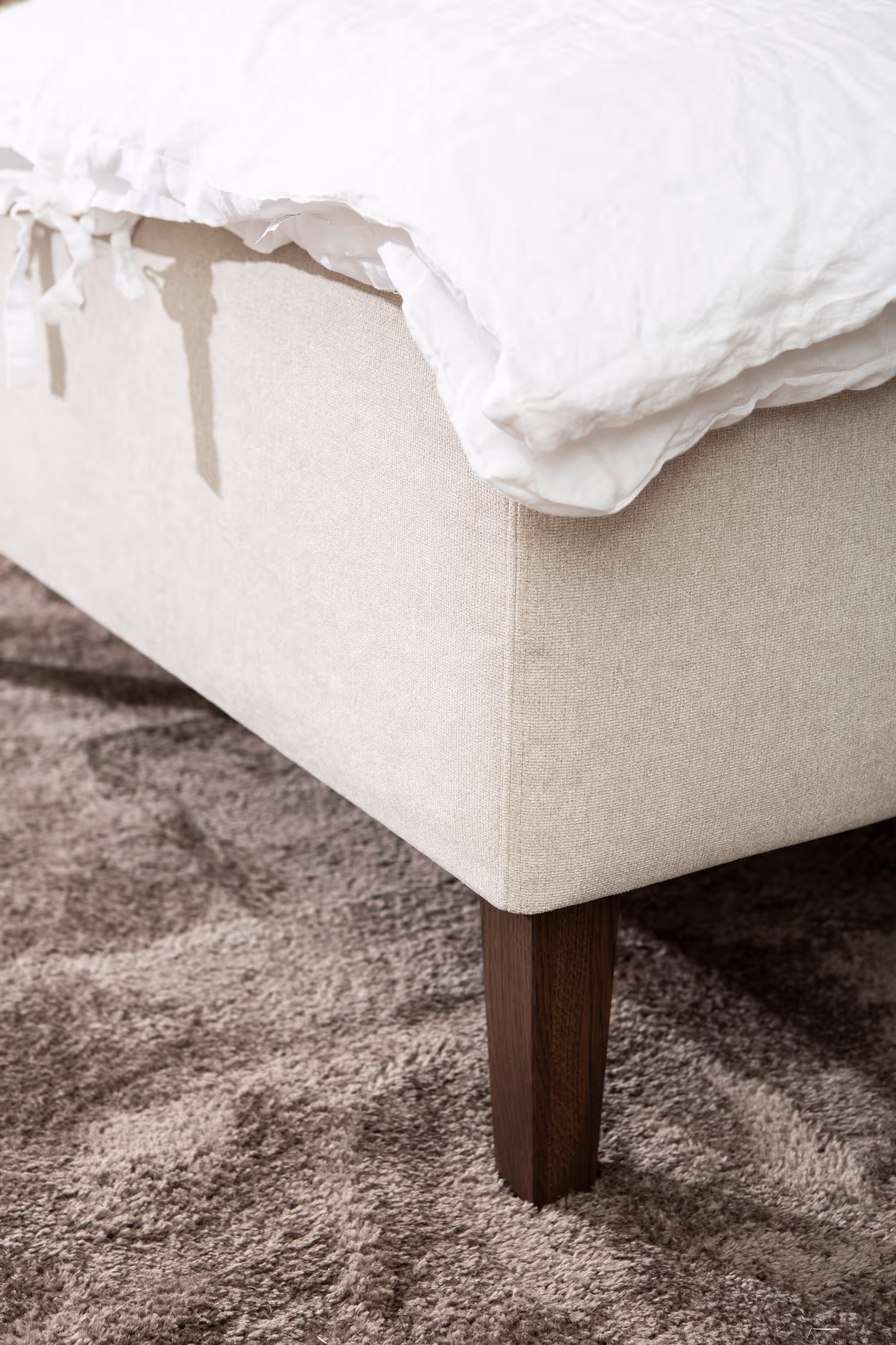 Oak-stained wooden legs of Moon Gold divan bed providing a light and natural touch that complements the beige upholstery.