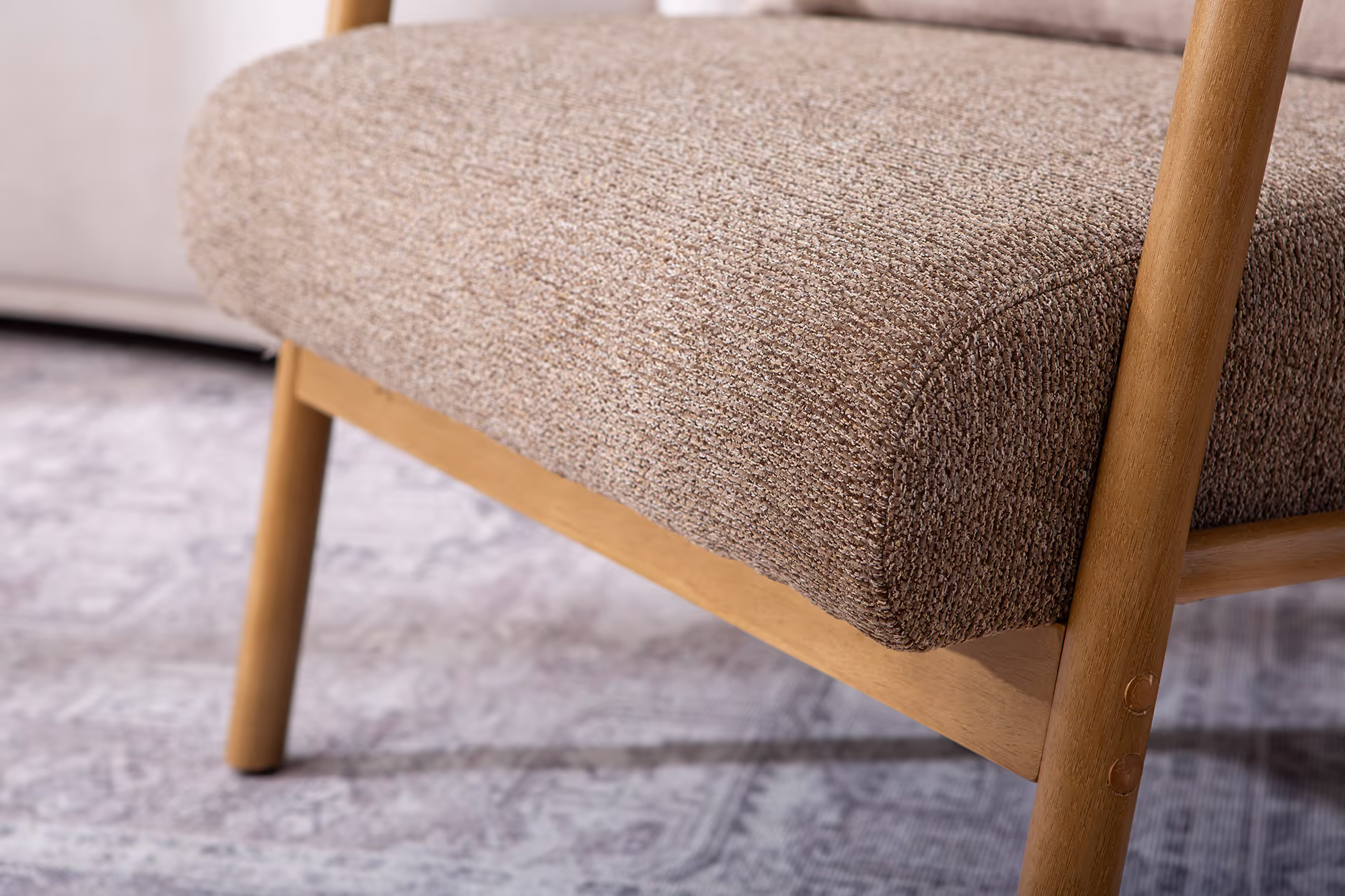 Dove armchair showing its natural rubberwood frame and brown fabric upholstery, angled view