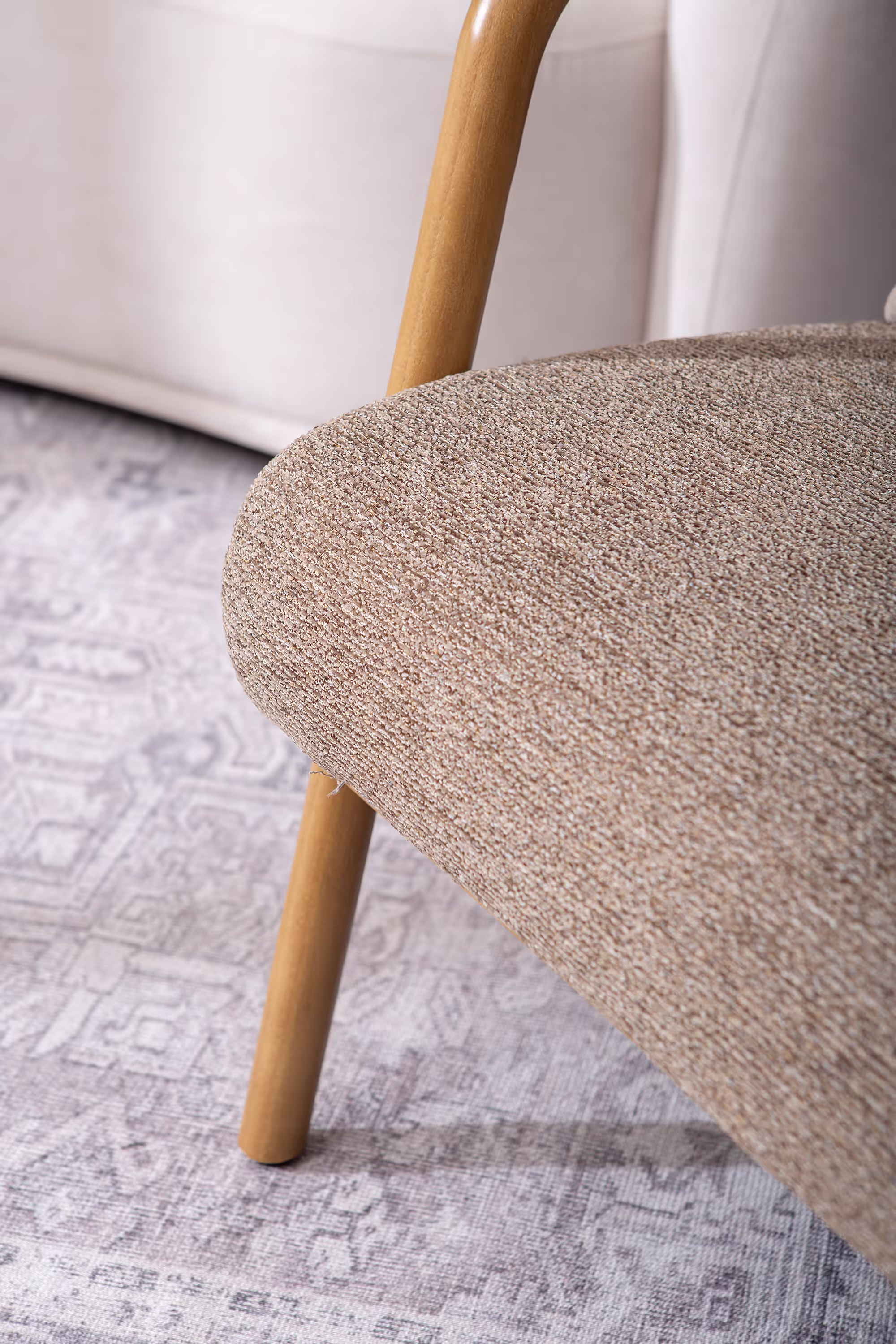 Close-up of Dove armchair’s cushioned brown fabric seat and backrest with natural rubberwood frame