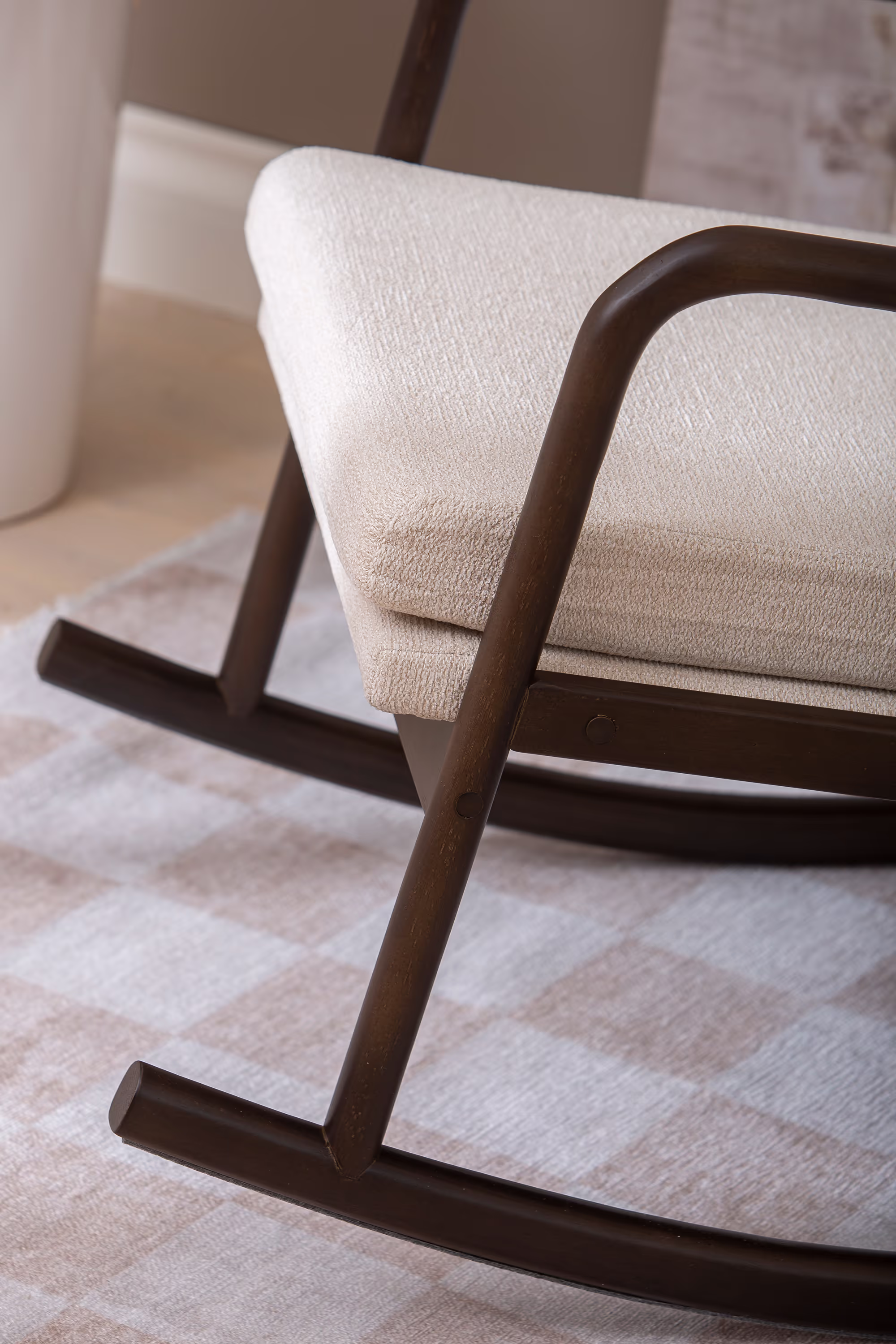 Swan rocking chair in beige fabric with walnut rubberwood frame, angled side view showcasing curved rocking legs and comfortable armrests.
