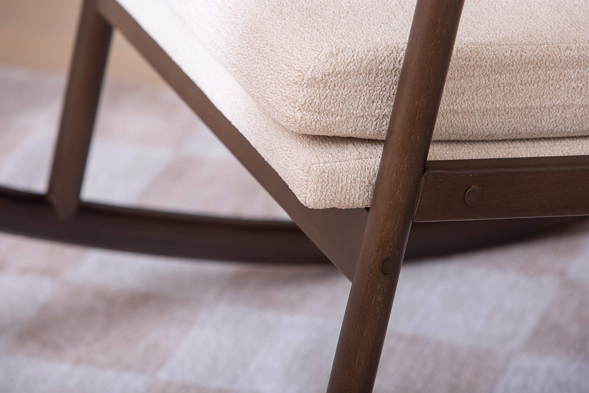Front-facing view of Swan rocking chair emphasizing high backrest and padded armrests in beige fabric.