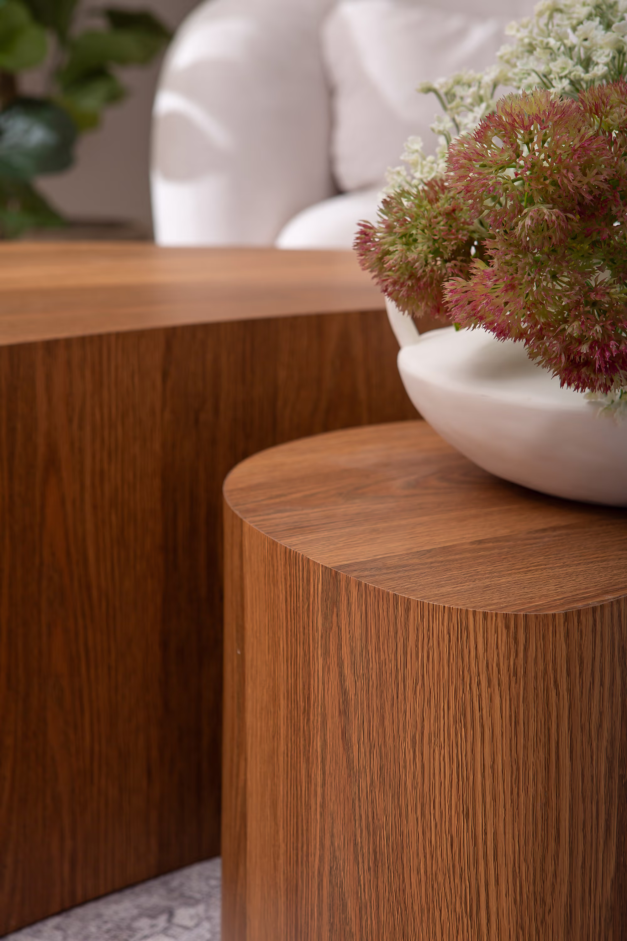 Smaller table from the Island series shown in front of a modern sofa, emphasizing its versatility as side table
