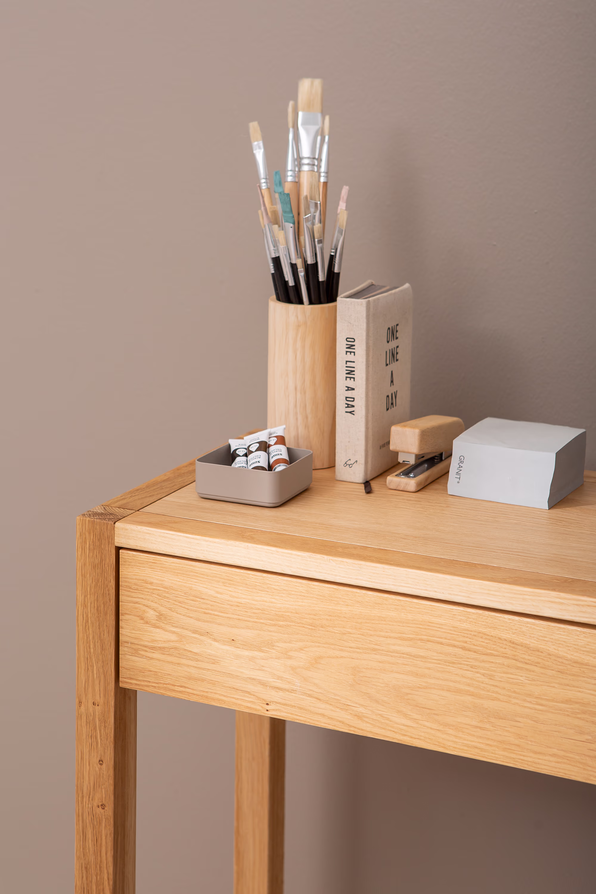 Oak console table with two drawers and slender legs contrast against light floor